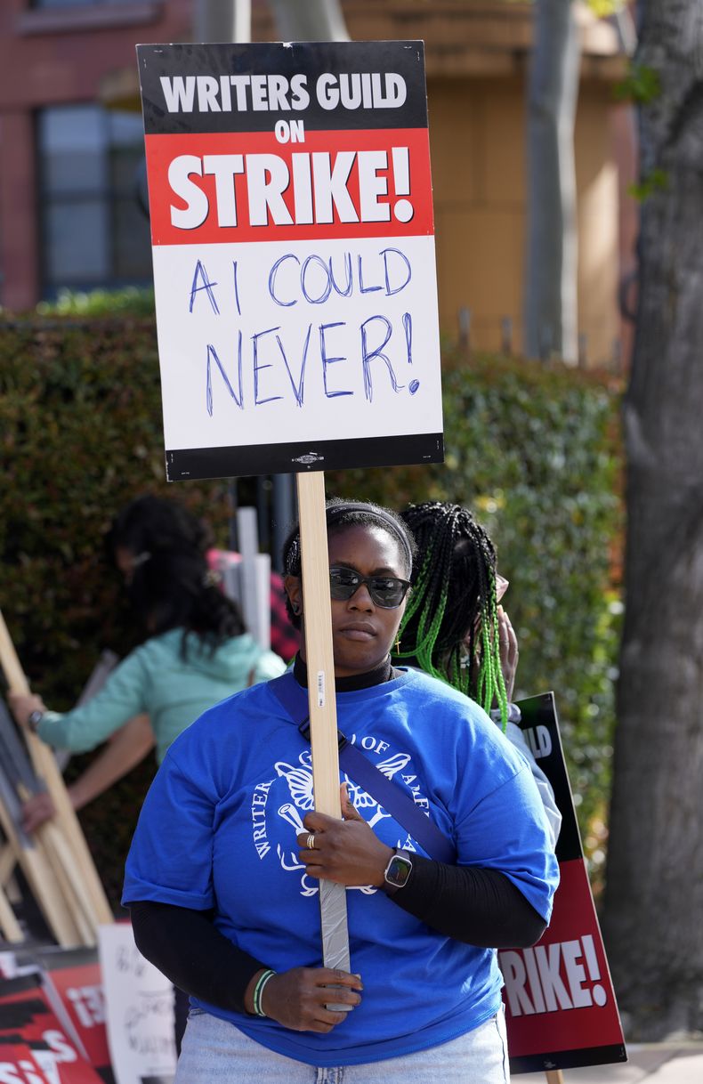 Chikodili Agwuna, guionista de la serie de televisión Criminal Minds, sostiene un cartel en una manifestación del Sindicato de Guionistas de Estados Unidos frente a Walt Disney Studios, el martes 2 de mayo de 2023, en Burbank, California. Una de las peticiones de los guionistas es revisar el uso de Inteligencia Artificial (IA) en la escritura de guiones. (Foto AP/Chris Pizzello)