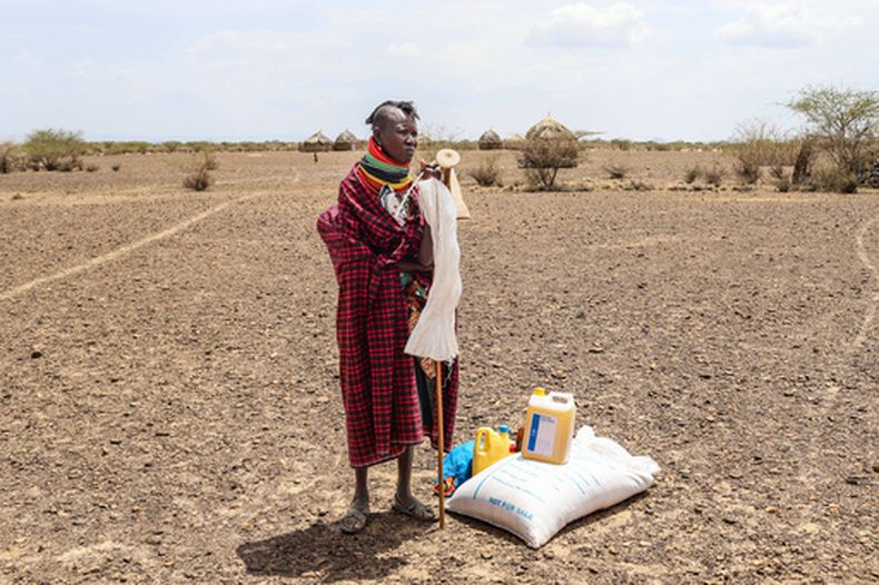 ARCHIVO - Una mujer se ve junto a su ración de comida tras un reparto de ayuda en el poblado de Nalemkais, condado de Turkana, Kenia, el 8 de febrero de 2026. (AP Foto/Patrick Ngugi, Archivo)