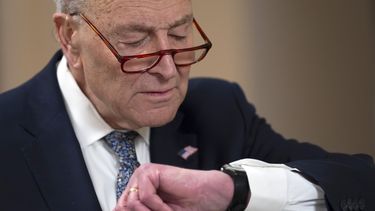 El líder de la minoría en el Senado, Chuck Schumer, revisa su reloj durante una entrevista en el Capitolio, Washington, el viernes 14 de marzo de 2025. (AP Foto/Ben Curtis)