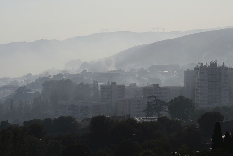 El humo provocado por un incendio forestal se eleva por detrás de los edificios del distrito de La Castellane, en Marsella, en el sur de Francia, el 8 de julio de 2025. (AP Foto/Lewis Joly)