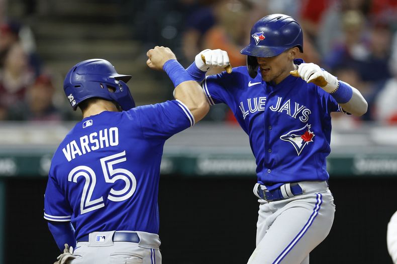 Cavan Biggio de los Azulejos de Toronto celebra con Daulton Varsho tras pegar un jonrón de dos carreras en la octava entrada frente al relevista de los Guardianes de Cleveland Enyel De Los Santos el lunes 7 de agosto del 2023. (AP Foto/Ron Schwane)