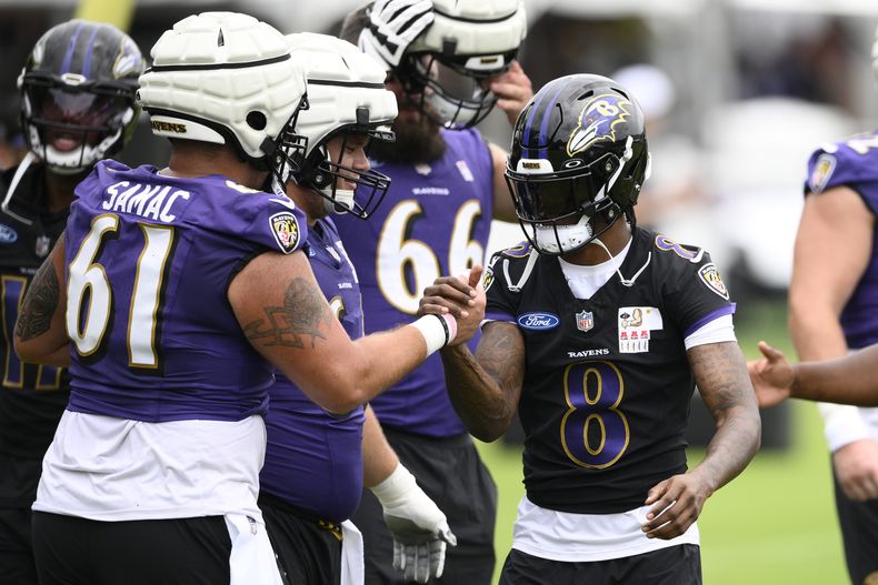 Lamar Jackson (8), quarterback de los Ravens de Baltimore, saluda al centro Nick Samac (61) durante el campo de entrenamiento de la NFL, el miércoles 24 de julio de 2024, en Owings Mills, Maryland. (AP Foto/Nick Wass)