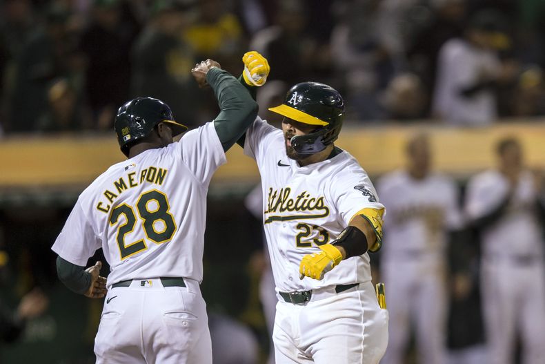 Shea Langeliers, de los Atléticos de Oakland, es felicitado por Daz Cameron, tras batear un jonrón de dos carreras ante los Mellizos de Minnesota, el viernes 21 de junio de 2024 (AP Foto/John Hefti)