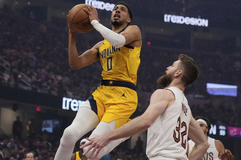 Tyrese Haliburton (0), de los Pacers de Indiana, ataca la canasta frente Dean Wade (32), de los Cavaliers de Cleveland, en la primera mitad del primer juego de las semifinales de la Conferencia Este del baloncesto de la NBA, el domingo 4 de mayo de 2025, en Cleveland. (AP Foto/Sue Ogrocki)