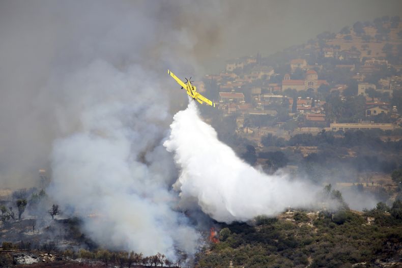 Un avión arroja agua sobre un incendio en Apesia, en el suroeste de Chipre, el 7 de agosto de 2023. (Foto AP/Philippos Christou)
