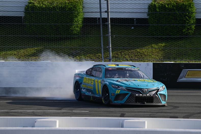 Denny Hamlin festeja en su auto tras ganar la carrera de la Copa NASCAR en Pocono Raceway, el domingo 23 de julio de 2023, en Long Pond, Pensilvania. (AP Foto/Derik Hamilton)