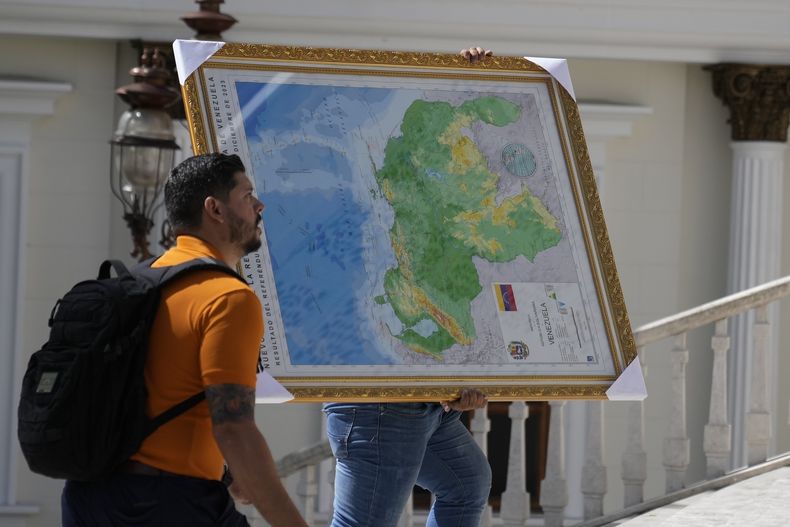Un hombre carga un mapa de Venezuela que incluye el territorio de Esequibo hacia la sede de la Asamblea Nacional en Caracas, Venezuela, el miércoles 6 de diciembre de 2023. (AP Foto/Ariana Cubillos)