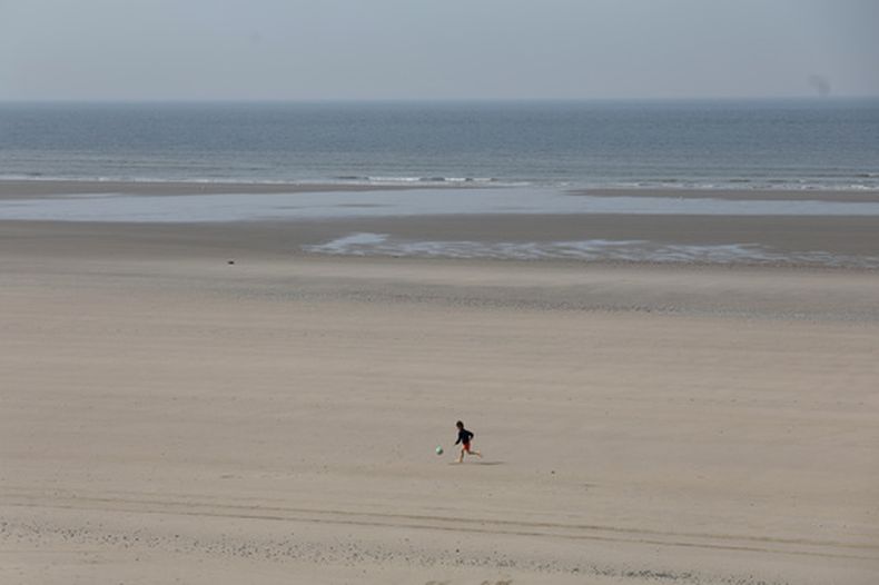 Un niño corre por una playa luego de que al menos cuatro personas fallecieron cuando trataban de subir a una balsa para cruzar desde el norte de Francia a Reino Unido, en Equihen-Plage, en el norte de Francia, el 9 de abril de 2026. (AP Foto/Jean-Francois Badias)