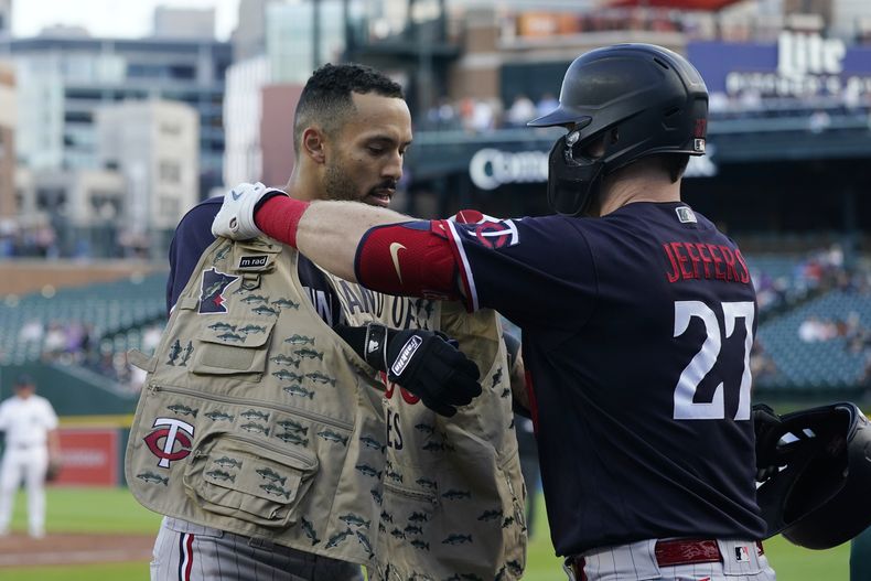 El puertorriqueño Carlos Correa de los Mellizos de Minnesota recibe de su compañero de equipo Ryan Jeffers (27) el chaleco de pesca alusivo a Minnesota luego de conectar cuadrangular de tres carreras ante los Tigres de Detroit, en Detroit. Lunes 7 de agosto de 2023. (AP Foto/Carlos Osorio)
