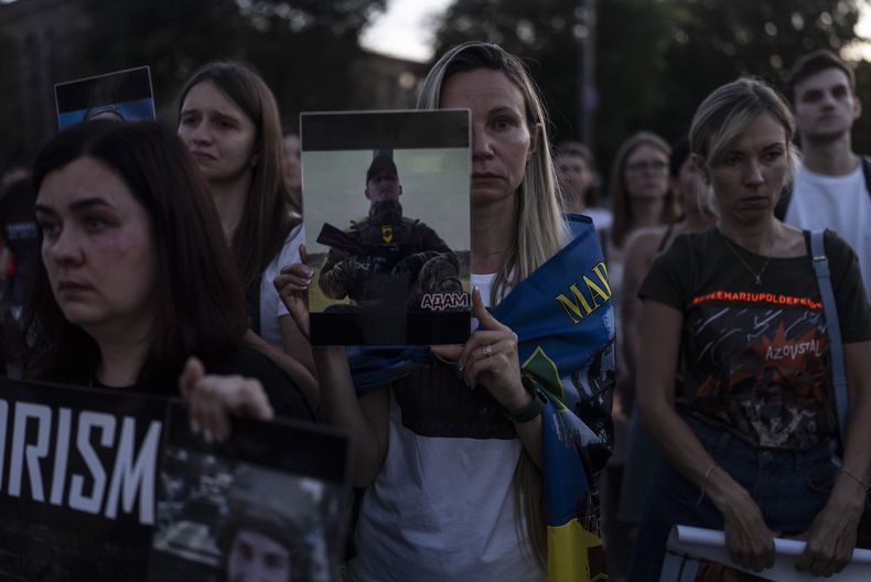Una mujer sostiene una foto de un soldado ucraniano durante un encuentro ante la embajada rusa en Kiev, Ucrania, el sábado 29 de julio de 2023 para conmemorar el primer aniversario del ataque a un edificio penitenciario en Olenivka, en el este de Ucrania, que mató a docenas de presos militares ucranianos. (AP Foto/Jae C. Hong)