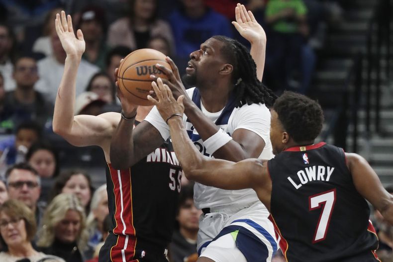 Naz Reid, pívot de los Timberwolves de Minnesota, salta hacia la canasta entre Duncan Robinson y Kyle Lowry, del Heat de Miami, el sábado 28 de octubre de 2023 (AP Foto/Bruce Kluckhohn)