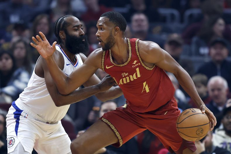 Evan Mobley (4), de los Cavaliers de Los Ángeles, conduce el balón ante la presión defensiva de James Harden, de los Clippers de Los Ángeles, durante la primera mitad del juego de baloncesto de la NBA, el lunes 29 de enero de 2024, en Cleveland. (AP Foto/Ron Schwane)