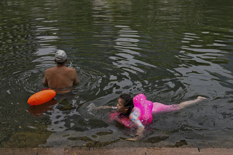 Vecinos nadando en un canal urbano para refrescarse en un día inusualmente caluroso en Beijing, el lunes 3 de julio de 2023. (AP Foto/Andy Wong)