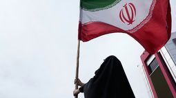 Una mujer sostiene una bandera iraní para una campaña progobierno en el centro de Teherán, Irán, el sábado 25 de abril de 2026. (AP Foto/Vahid Salemi)