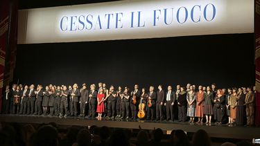 Miembros de la compañía de danza y de la orquesta de La Scala se mantienen de pie en el escenario antes de la última presentación de la ópera-ballet Madina, el sábado 9 de marzo de 2024, en Milán, Italia. La pancarta encima de ellos dice: Alto al fuego. (AP Foto/Colleen Barry)
