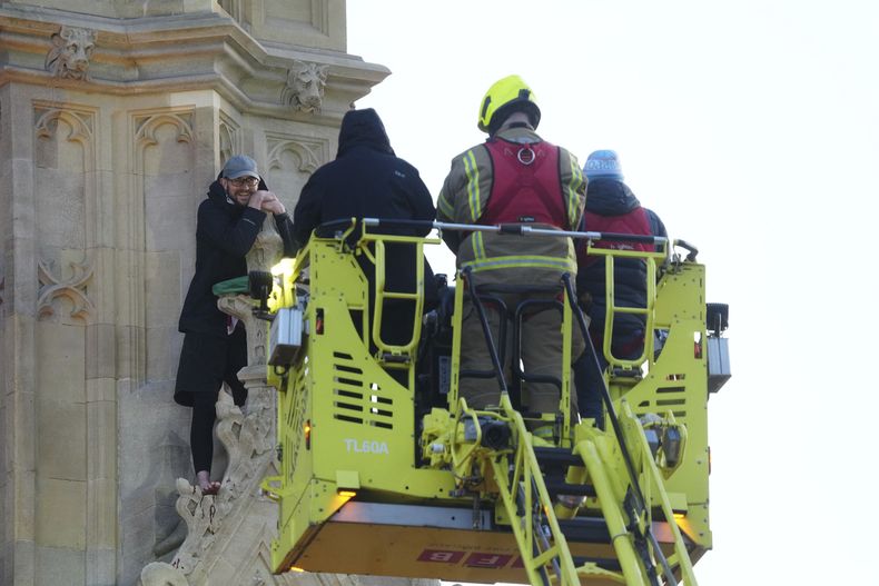 Trabajadores de emergencias hablan con un hombre que trepó a la torre Elizabeth, que incluye el Big Ben, en el palacio de Westminster en Londres, el sábado, el 8 de marzo de 2025. (Jeff Moore/PA via AP)