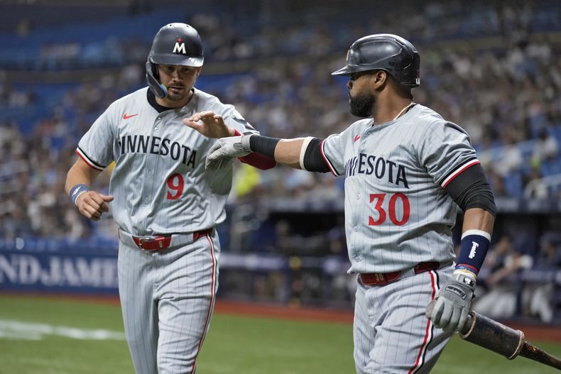 Trevor Larnach (9) de los Mellizos de Minnesota celebra con el bateador dominicano en el círculo de espera, Carlos Santana (30) luego de anotar en un doblete productivo de Royce Lewis ante el abridor de los Rays de Tampa Bay, Zack Little, durante la primera entrada del juego de béisbol el lunes 2 de septiembre de 2024, en San Petersburgo, Florida. (AP Foto/Chris OMeara)
