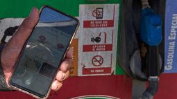 El jubilado Jorge Reyes muestra su teléfono con la aplicación El Ticket, que se utiliza para reservar un lugar en la fila para comprar gasolina racionada en La Habana, Cuba, el lunes 16 de febrero de 2026. (Foto AP/Ramón Espinosa)
