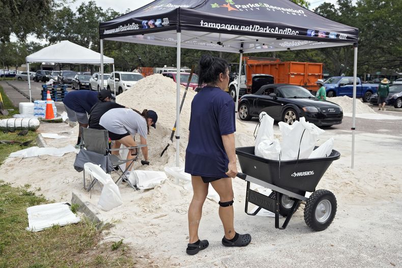 Elementos del Departamento de Parques y Recreación de Tampa, Florida, entregan costales de arena a los residentes, el lunes 28 de agosto de 2023, en Tampa. (AP Foto/Chris OMeara)