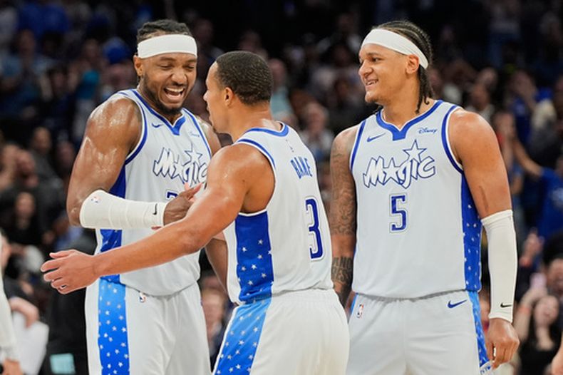 Wendell Carter Jr., pívot del Magic de Orlando, y su compañero Paolo Banchero (5), felicitan a Desmond Bane, quien anotó un triple en los últimos instantes del partido del miércoles 11 de marzo de 2026, ante los Cavaliers de Cleveland (AP Foto/John Raoux)