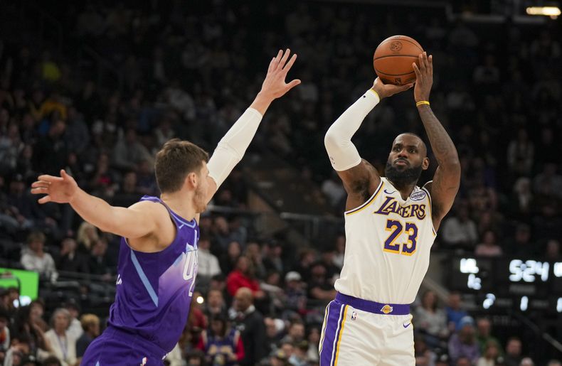 LeBron James (23), de los Lakers de Los Ángeles, dispara ante la presión defensiva de Walker Kessler, del Jazz de Utah, durante la priemra mitad del juego de baloncesto de la NBA, el domingo 1 de diciembre de 2024, en Salt Lake City. (AP Foto/Bethany Baker)
