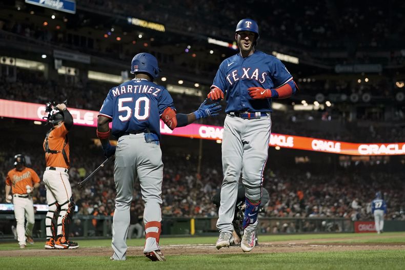Mitch Garver, derecha, de los Rangers de Texas, celebra con Juan Pablo Martínez (50) después de batear un cuadrangular solitario en contra de los Gigantes de San Francisco durante la sexta entrada del juego de béisbol, el viernes 11 de agosto de 2023, en San Francisco. (AP Foto/Godofredo A. Vásquez)