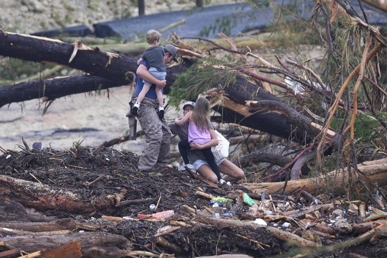 Una mujer se cae mientras camina entre escombros en un puente sobre el río Guadalupe luego de que una inundación repentina azotó la zona, el sábado 5 de julio de 2025, en Ingram, Texas. (AP Foto/Julio Cortez)