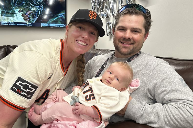Alyssa Nakken, coach asistente de los Gigantes de San Francisco, posa junto a su marido Robert y a su hija Austyn, antes de un juego ante los Padres de San Diego, el viernes 5 de abril de 2024 (AP foto/Janie McCauley)