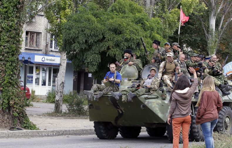 Residentes saludan a rebeldes pro rusos que viajan en un veh&iacute;culo blindado durante un desfile en Lugansk, este de Ucrania, el domingo 14 de septiembre de 2014. (Foto AP/Darko Vojinovic)