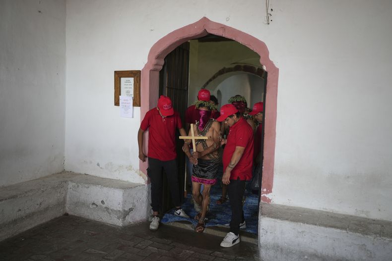 Un penitente enmascarado, con cadenas sobre los hombros, es conducido por otras personas para participar en una procesión el Viernes Santo, 18 de abril de 2025, en Atlixco, México. (AP Foto/Eduardo Verdugo)