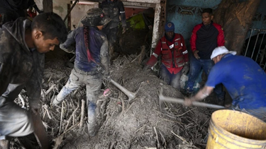 Los residentes ayudan a los rescatistas a desenterrar el lodo de las casas destruidas mientras buscan víctimas o sobrevivientes de un deslizamiento de tierra durante las fuertes lluvias en Las Tejerias, estado de Aragua, Venezuela, el 9 de octubre de 2