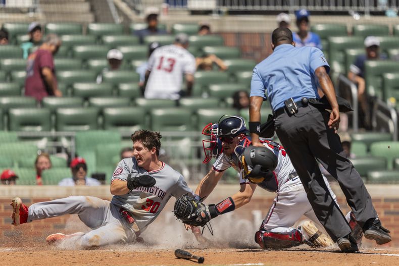 Jacob Young de los Nacionales de Washington anota una carrera al deslizarse en el plato frente al receptor Sean Murphy de los Bravos de Atlanta, el domingo 25 de agosto de 2024. (AP Foto/Jason Allen)