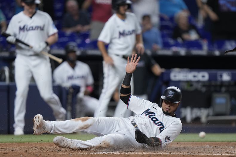 El venezolano Luis Arráez, de los Marlins de Miami, se desliza en el plato para anotar en el juego del martes 6 de junio de 2023, ante los Reales de Kansas City (AP Foto/Wilfredo Lee)