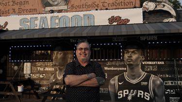 El empresario y seguidor de los Spurs de San Antonio Roland Ramirez posa con el mural del francés Victor Wembanyama que realizó el artista Nik Soupe afuera de su restaurante de mariscos en San Antonio el jueves 15 de junio del 2023. (AP Foto/Eric Gay)
