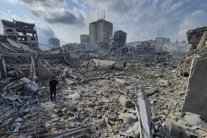 Palestinos caminan sobre los escombros de edificios destruidos por los ataque aéreos de Israel en Gaza, el martes 10 de octubre de 2023. (AP Foto/Hassan Eslaiah)