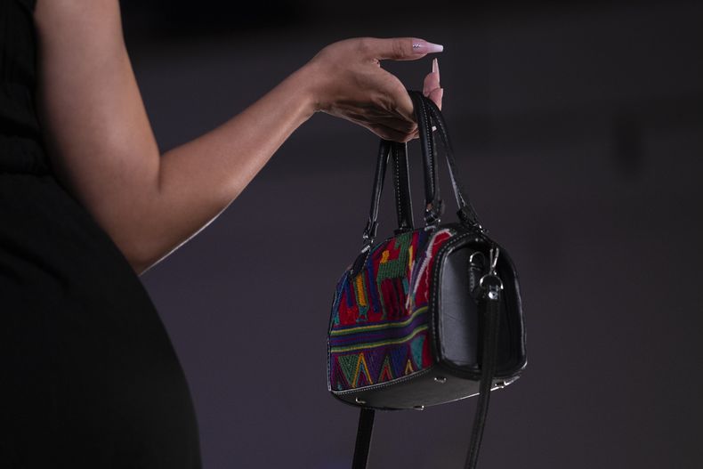 Una modelo muestra un bolso durante un desfile de modas con textiles guatemaltecos, el viernes 12 de mayo de 2023, en Brownsville, Texas. Una diseñadora nacida en Guatemala combinó técnicas indígenas de tejido, diseño moderno de ropa y colorida historia de su país natal en una exhibición reciente en una pasarela de Texas. La presentación ofreció una muestra no sólo de la visión artística de Elena de León, sino un trabajo de madres guatemaltecas, incluidas algunas que viven en Estados Unidos y otras que se quedaron en su país para apoyar a sus familias. (AP Foto/Julio Cortez)
