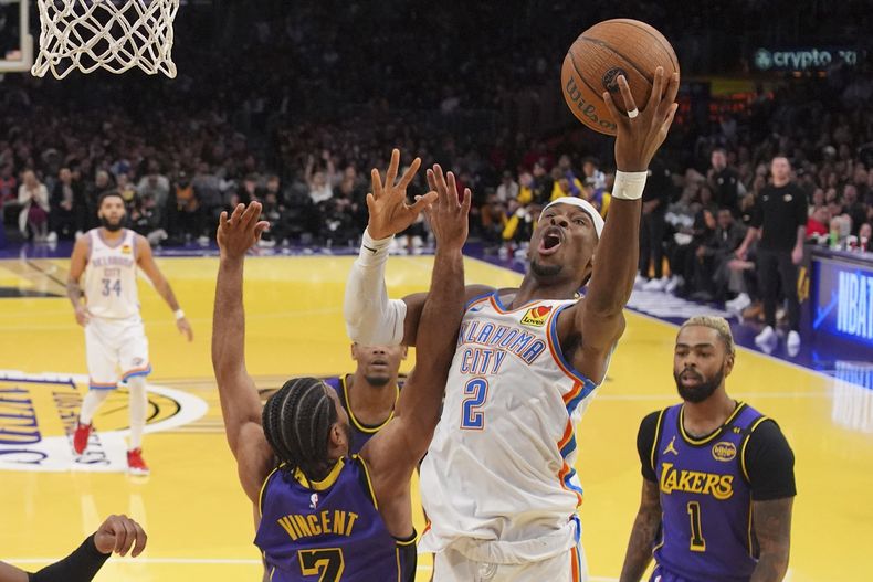 Shai Gilgeous-Alexander, del Thunder de Oklahoma City, dispara frente a Gabe Vincent y DAngelo Russell, de los Lakers de Los Ángeles, el viernes 29 de noviembre de 2024 (AP Foto/Mark J. Terrill)