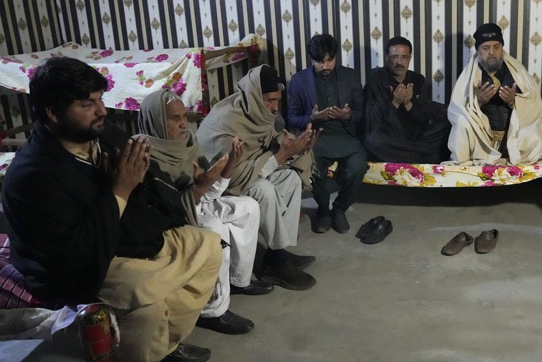 Ahsan Shahzad, padre de Suffian Ali, uno de los migrantes que falleció en el naufragio de un bote frente a la costa atlántica de África Occidental, es consolado por familiares, en su hogar en la aldea de Dhola, en el distrito de Lalamusa, Pakistán, el viernes 17 de enero de 2024. (AP Foto/K.M. Chaudary)