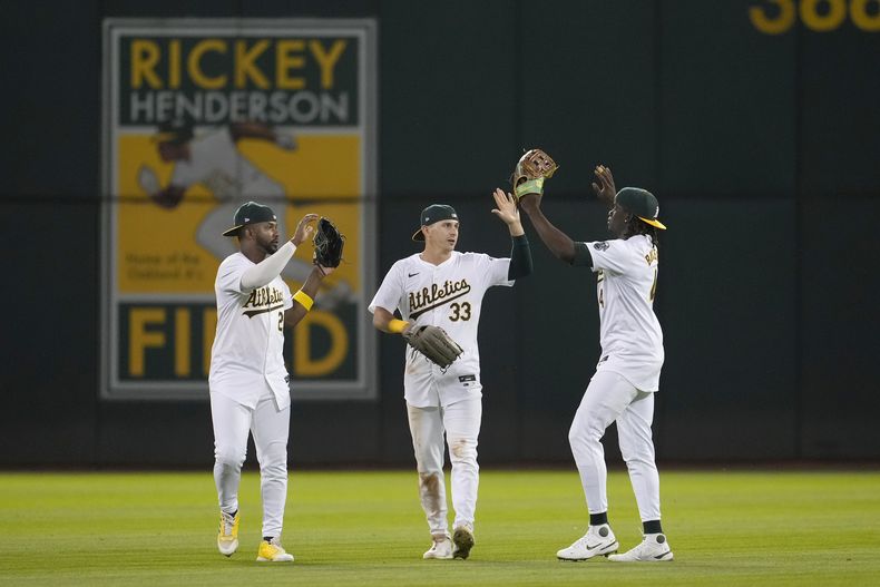 El jardinero izquierdo de los Atléticos de Oakland, Miguel Andújar, de izquierda a derecha, celebra con el jardinero central JJ Bleday y el jardinero derecho Lawrence Butler después de que los Atléticos derrotaron a los Astros de Houston en Oakland, California, el lunes 22 de julio de 2024. (AP Foto/Jeff Chiu)