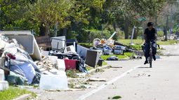Un ciclista pasa al lado de escombros y artículos de viviendas dañados en St. Petersburg, Florida, un día después del paso del huracán Milton por la región, el jueves 10 de octubre de 2024. (AP Foto/Julio Cortez)
