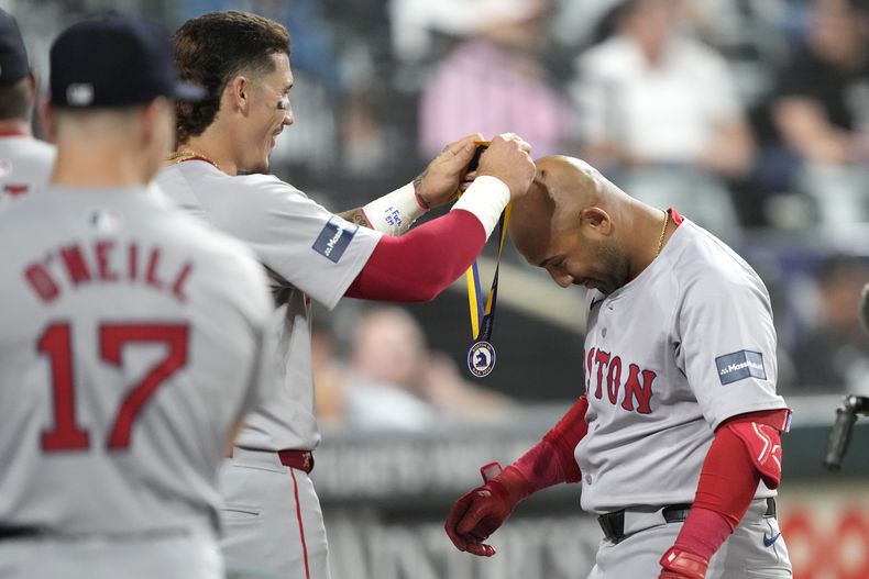 Jarren Duran (izquierda) de los Medias Rojas de Boston cuelga una medalla a su compañero Jamie Westbrook tras el jonrón de Westbrook ante los Medias Blancas de Chicago, el jueves 6 de junio de 202, en Chicago. (AP Photo/Charles Rex Arbogast)