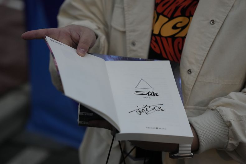 Tao Bolin, un influencer de 25 años y fanático de la ciencia ficción, sostiene una copia firmada de El problema de los tres cuerpos fuera de la Convención Mundial de Ciencia Ficción en Chengdu, provincia de Sichuan, el viernes 20 de octubre de 2023. El problema de los tres cuerpos, escrita por el ingeniero Liu Cixin, ayudó a la ciencia ficción china a abrirse paso a nivel internacional, ganando premios y llegando a las listas de lectura de personas como el ex presidente estadounidense Barack Obama y Mark Zuckerberg. (AP Photo/Ng Han Guan)