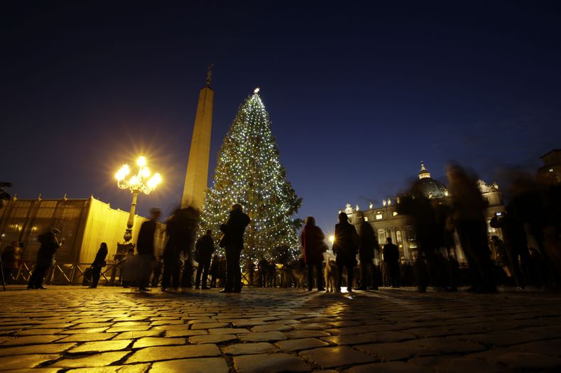 Turistas admiran el &aacute;rbol navide&ntilde;o encendido en el centro dela Plaza de San Pedro, en El Vaticano, el viernes, 13 de diciembre del 2013. EL abeto de 25 metros fue donado por una ciudad de Bavaria, Alemania.  (Foto AP/Andrew Medichini)