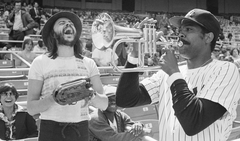 ARCHIVO - El lanzador de los Yankees de Nueva York, Dock Ellis, a la derecha, se divierte un poco con el cuerno de Chuck Mangione antes de un juego con los Blue Jays de Toronto en el Yankee Stadium, el 19 de abril de 1977, en Nueva York. (Foto AP/Ray Stubblebine, archivo)