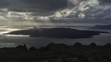 Los rayos del sol iluminan el islote volcánico de Nea Kameni, parte de la isla de Santorini afectada por el terremoto, Grecia, martes 4 de febrero de 2025. (AP foto/Petros Giannakouris)