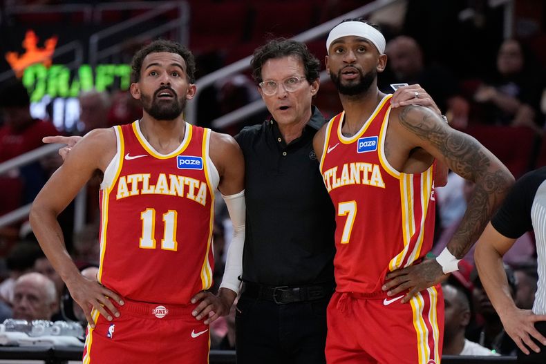 Quin Snyder, centro, entrenador de los Hawks de Atlanta, habla con Trae Young (11) y Nickeil Alexander-Walker (7) durante la primera mitad del partido de pretemporada de baloncesto de la NBA en contra de los Rockets de Houston, el lunes 6 de octubre de 2025, en Houston. (AP Foto/Ashley Landis)