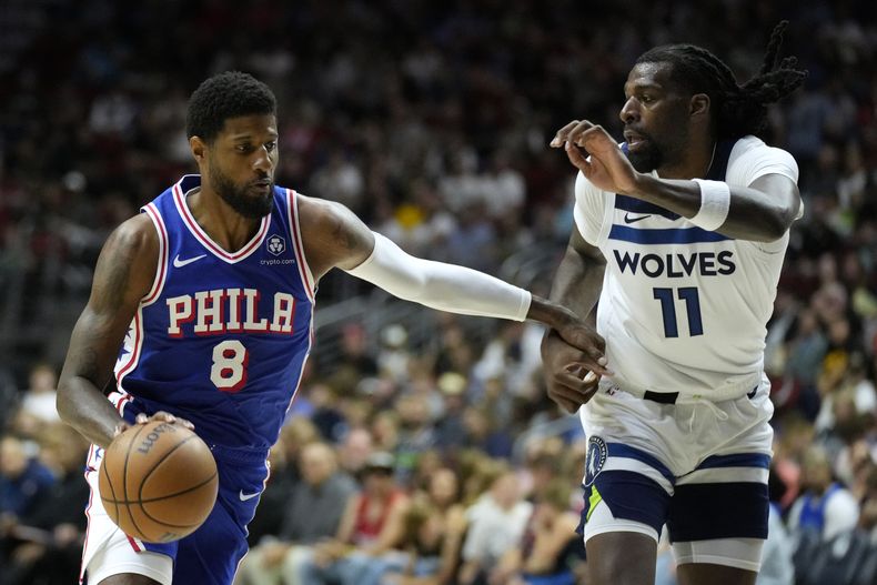 Paul George (8) de los 76ers de Filadelfia conduce el balón ante Naz Reid (11) de los Timberwolves de Minnesota, el viernes 11 de octubre de 2024, en Des Moines, Iowa. (AP Foto/Charlie Neibergall)