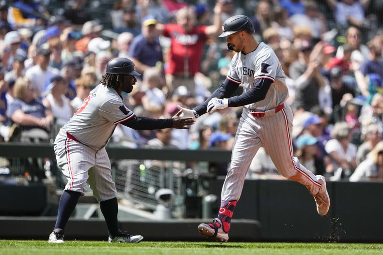 Trevor Larnach, de los Mellizos de Minnesota, celebra su cuadrangular de dos carreras en contra de los Marineros de Seattle con el coach de tercera Tommy Watkins mientras se efila rumbo al plato durante la octava entrada del juego de béisbol del domingo 30 de junio de 2024, en Seattle. (AP Foto/Lindsey Wasson)