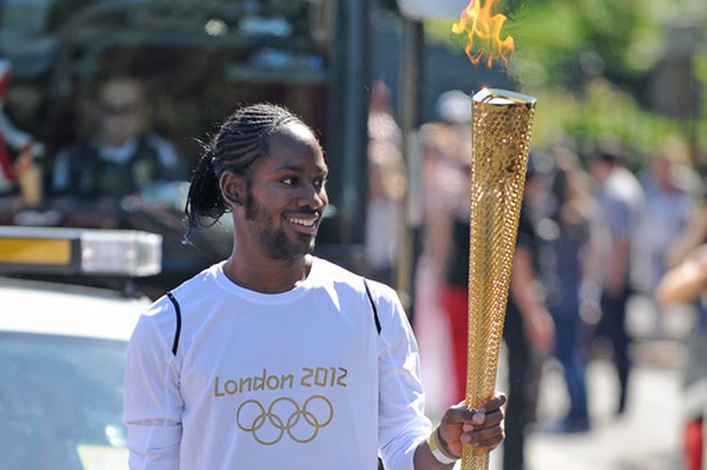 Jason Arday porta la Antorcha Olímpica en el tramo entre Sutton y Merton, Londres, el 23 de julio de 2012. (Joe Giddens/LOCOG/PA vía AP)
