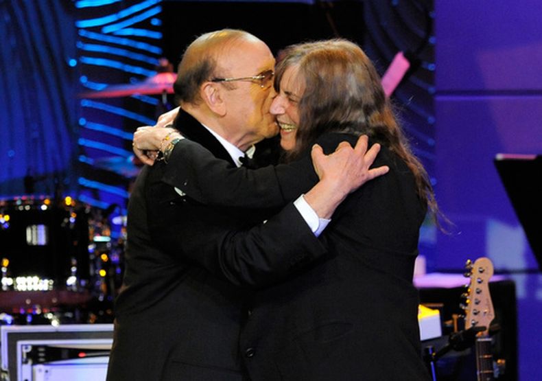 ARCHIVO - El productor musical Clive Davis, a la izquierda, y la artista Patti Smith se abrazan en el escenario durante la gala previa a los premios Grammy de Clive Davis en Beverly Hills, California, el 9 de febrero de 2013. (Foto Chris Pizzello/Invision/AP, archivo)